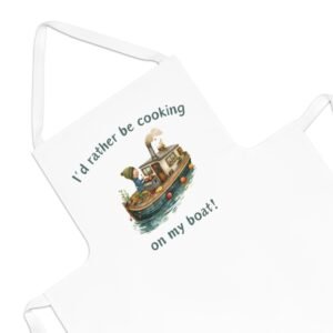 A white apron featuring an illustration of a woman cooking on a boat. Text on the apron reads, 'I'd rather be cooking on my boat!'